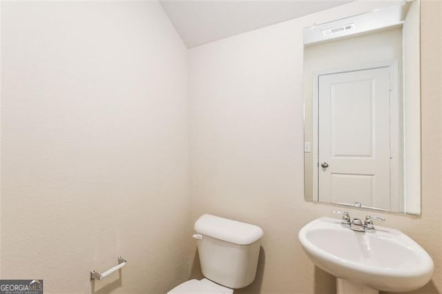 bathroom with vaulted ceiling, sink, and toilet