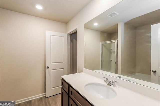 bathroom featuring hardwood / wood-style flooring, vanity, and a shower with shower door