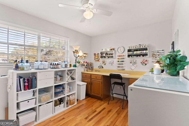 office area featuring ceiling fan, built in desk, and light hardwood / wood-style floors