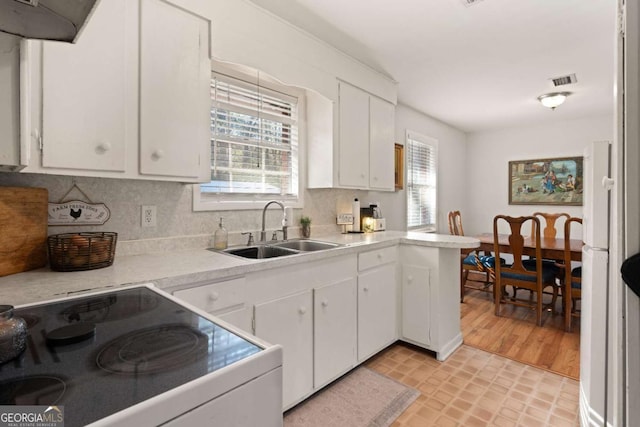 kitchen with electric stove, sink, tasteful backsplash, and white cabinets