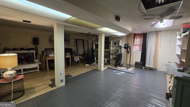 exercise room with dark hardwood / wood-style flooring, a paneled ceiling, and ceiling fan