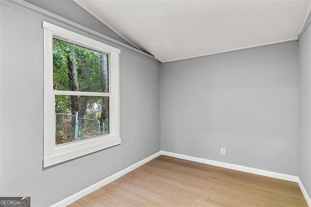 spare room featuring vaulted ceiling and light hardwood / wood-style floors