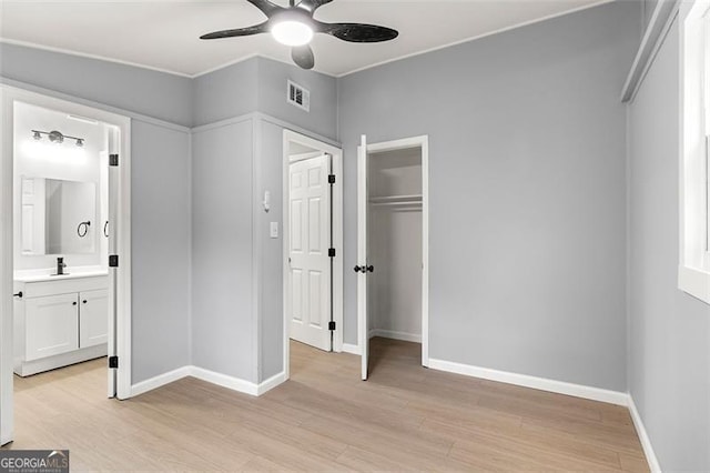 unfurnished bedroom with connected bathroom, sink, light wood-type flooring, a closet, and ceiling fan