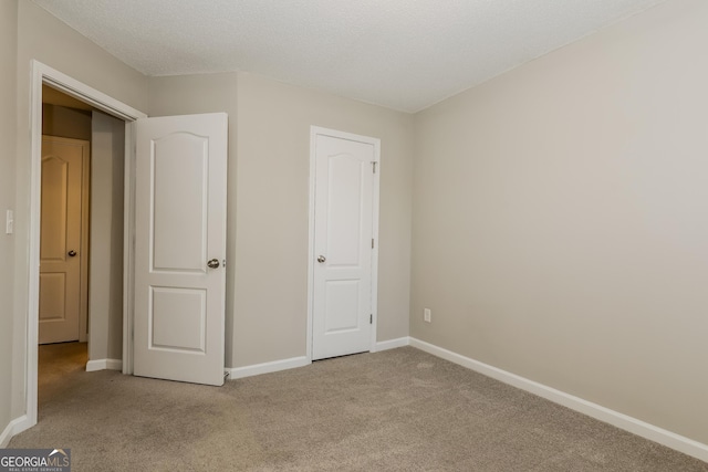 unfurnished bedroom with light colored carpet and a textured ceiling