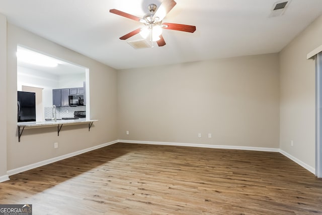 unfurnished living room featuring ceiling fan, wood-type flooring, and sink