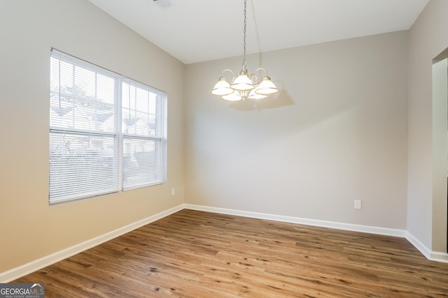 unfurnished room with wood-type flooring and a notable chandelier