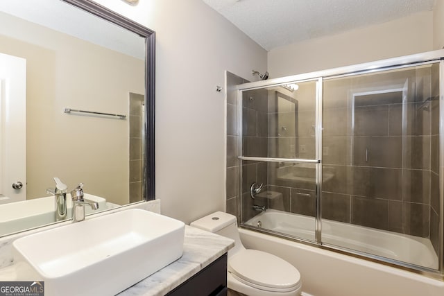 full bathroom featuring bath / shower combo with glass door, vanity, a textured ceiling, and toilet