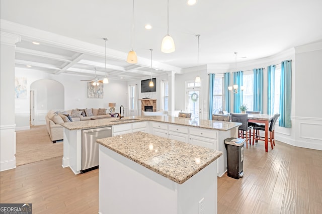 kitchen featuring sink, hanging light fixtures, a kitchen island, a stone fireplace, and stainless steel dishwasher