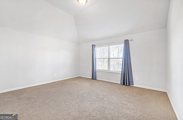 carpeted spare room with vaulted ceiling