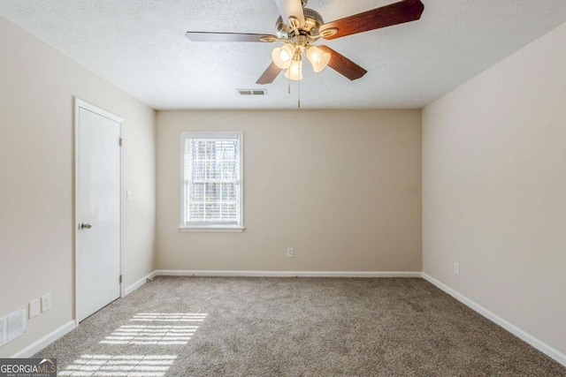 empty room featuring ceiling fan, light colored carpet, and a textured ceiling