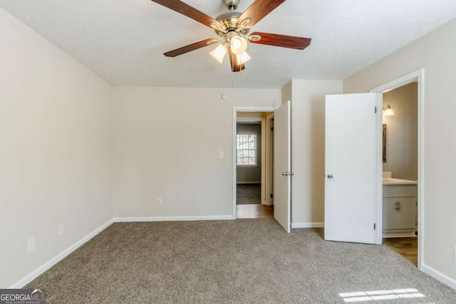 unfurnished bedroom featuring light colored carpet, ceiling fan, and ensuite bathroom