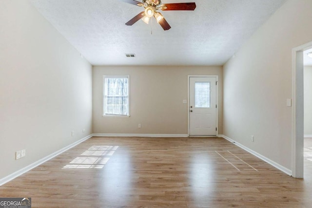 interior space with ceiling fan, plenty of natural light, light hardwood / wood-style floors, and a textured ceiling