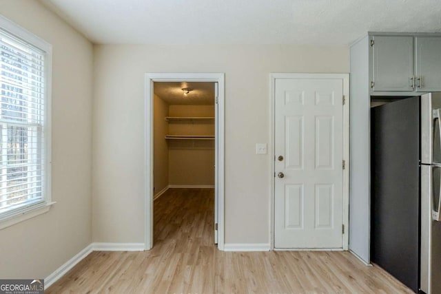 interior space with gray cabinetry, stainless steel fridge, and light hardwood / wood-style floors