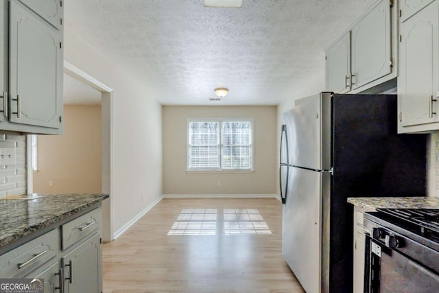 kitchen with white cabinetry, backsplash, light stone counters, a textured ceiling, and light wood-type flooring