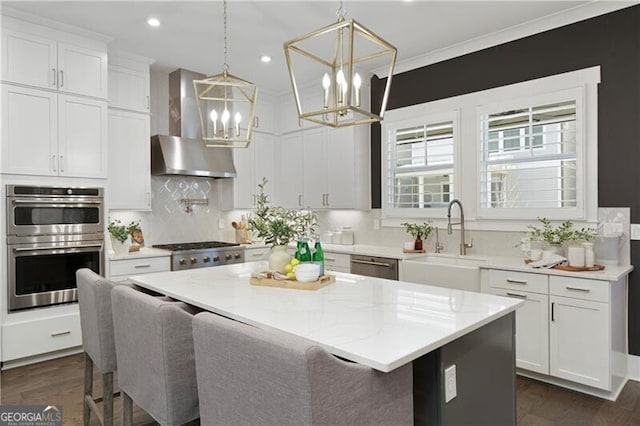 kitchen featuring white cabinetry, sink, pendant lighting, and wall chimney exhaust hood