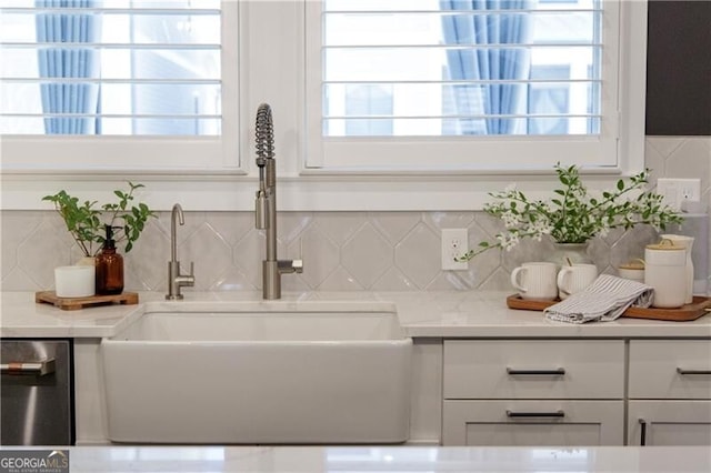 interior space with plenty of natural light, sink, stainless steel dishwasher, and white cabinets