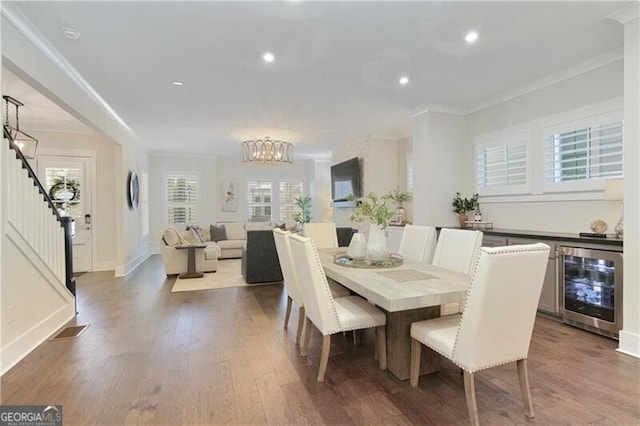 dining area featuring ornamental molding, dark wood-type flooring, beverage cooler, and an inviting chandelier