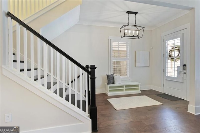 entryway with ornamental molding, dark hardwood / wood-style floors, and a notable chandelier