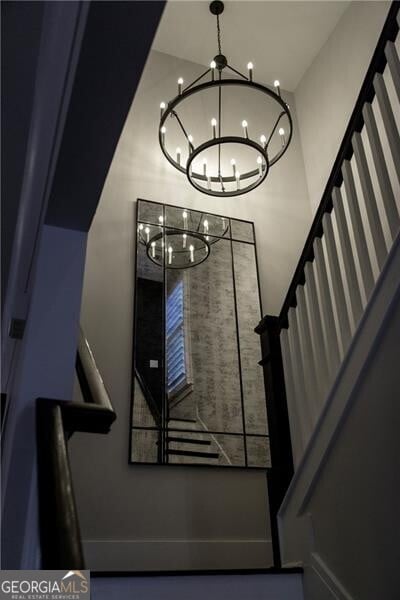 staircase with a notable chandelier