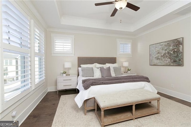 bedroom featuring crown molding, a tray ceiling, dark wood-type flooring, and ceiling fan