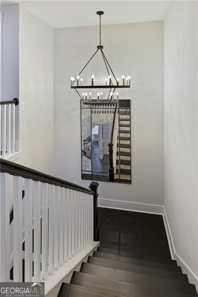 stairway with hardwood / wood-style flooring and an inviting chandelier