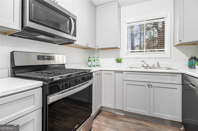 kitchen with white cabinetry, sink, wood-type flooring, and appliances with stainless steel finishes