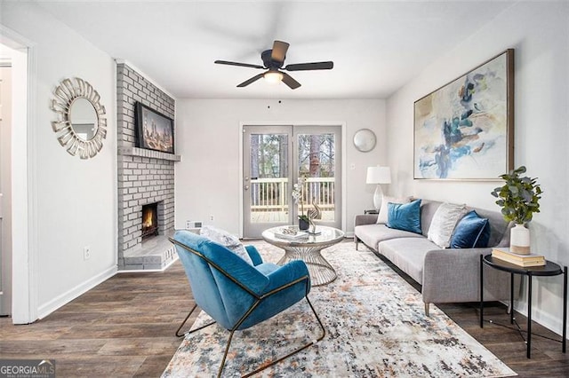 living room with a brick fireplace, dark hardwood / wood-style floors, and ceiling fan