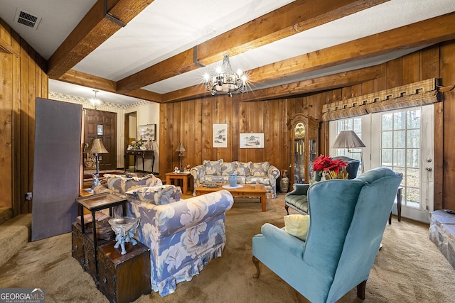 carpeted living room with beamed ceiling, a chandelier, and wood walls