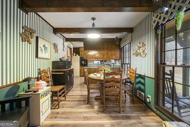 dining space with beam ceiling and light hardwood / wood-style floors