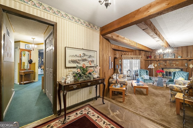 sitting room with an inviting chandelier, a textured ceiling, carpet, and beamed ceiling