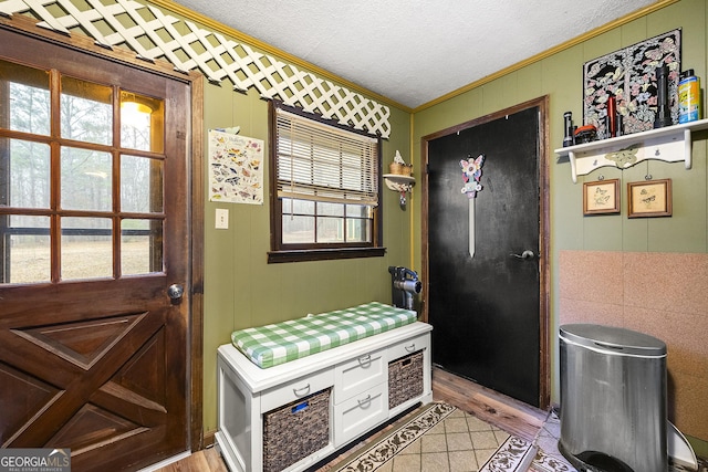 doorway featuring crown molding, light wood-type flooring, and a textured ceiling