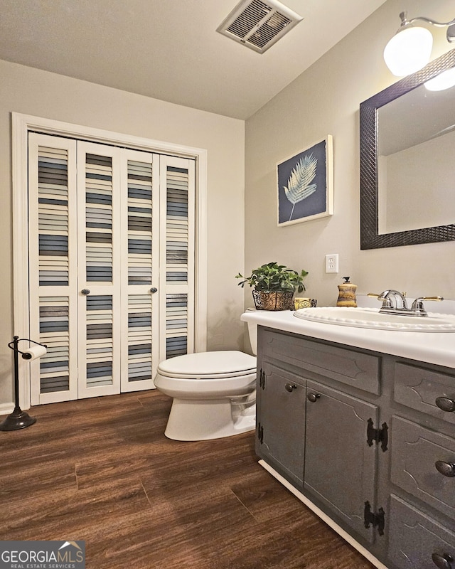 bathroom featuring wood-type flooring, toilet, and vanity