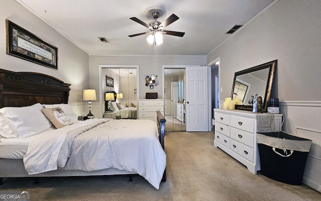 carpeted bedroom with multiple closets, crown molding, and ceiling fan