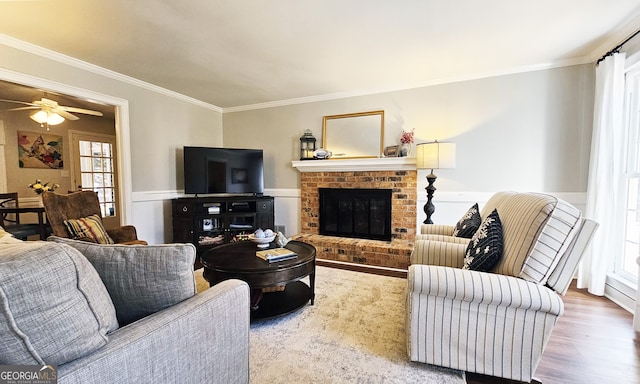 living room featuring hardwood / wood-style flooring, crown molding, a brick fireplace, and ceiling fan