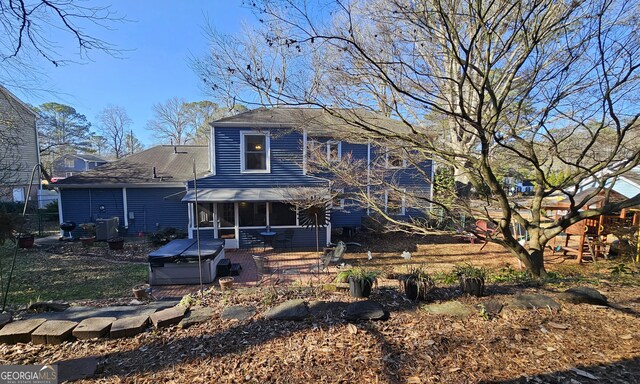 rear view of house featuring a patio area and a hot tub