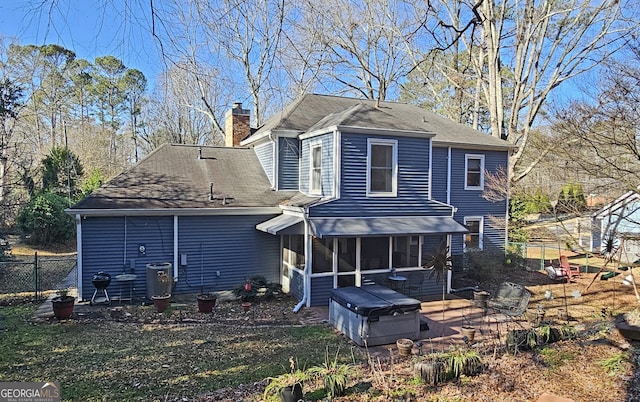 rear view of property featuring a hot tub, a patio, and a sunroom