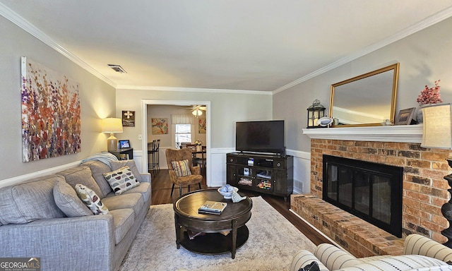 living room featuring hardwood / wood-style floors, crown molding, a fireplace, and ceiling fan