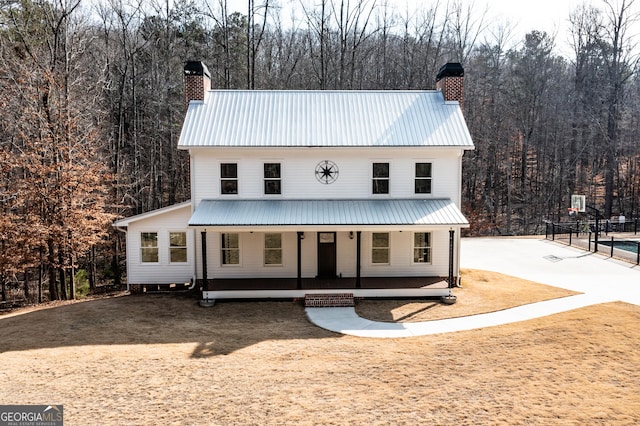 modern farmhouse style home with covered porch, a chimney, and metal roof