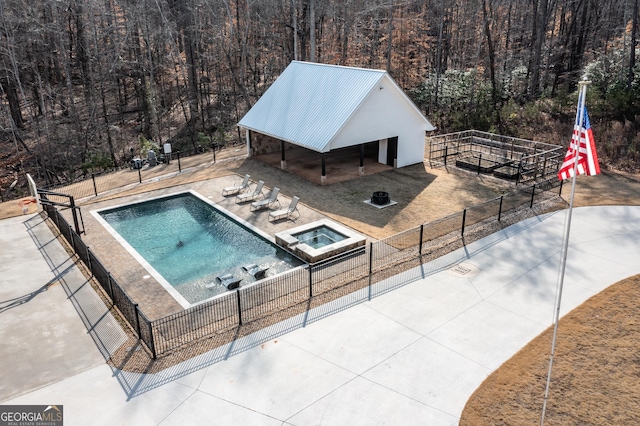 view of pool featuring an outdoor fire pit, fence, a view of trees, and an outbuilding