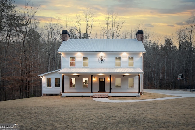 view of front facade featuring metal roof, a chimney, a porch, and a ceiling fan