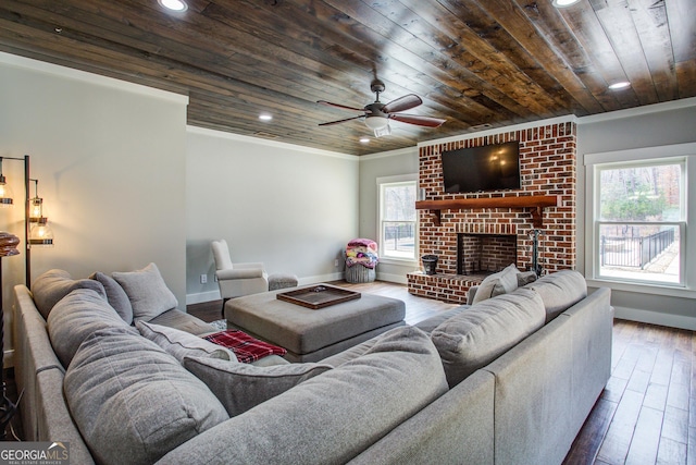 living room with baseboards, hardwood / wood-style flooring, wood ceiling, ornamental molding, and a brick fireplace