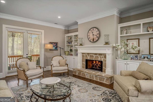 living area with crown molding, a stone fireplace, french doors, and light wood-type flooring