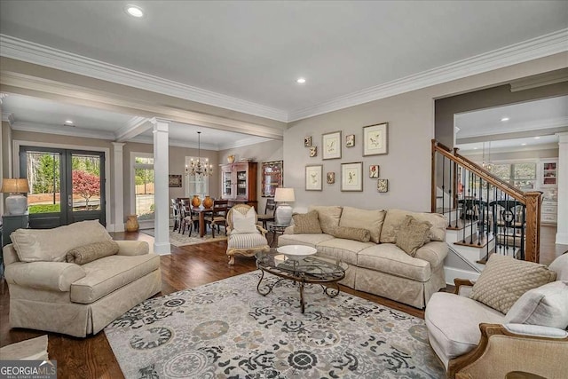 living room with an inviting chandelier, crown molding, decorative columns, and hardwood / wood-style floors