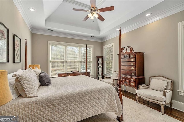 bedroom featuring hardwood / wood-style flooring, crown molding, ceiling fan, and a tray ceiling