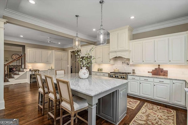kitchen with light stone counters, custom range hood, backsplash, dark wood-style flooring, and recessed lighting