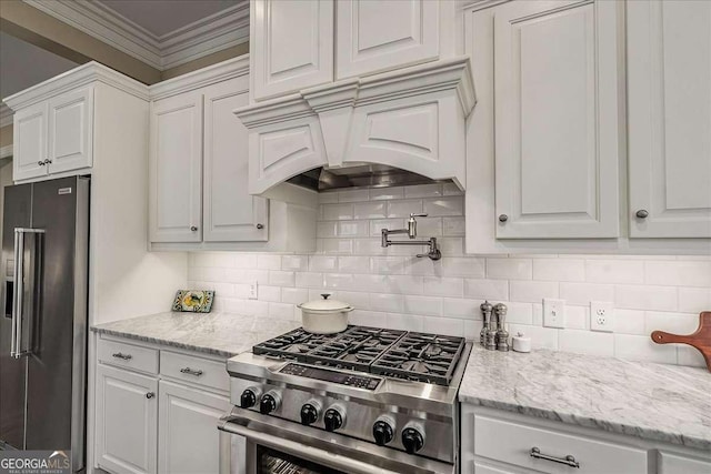 kitchen with premium appliances, premium range hood, backsplash, white cabinetry, and light stone countertops