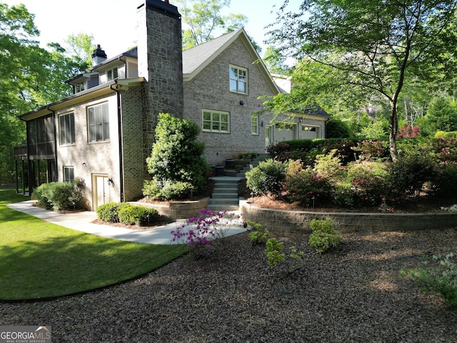 rear view of house with brick siding, a chimney, and stairs