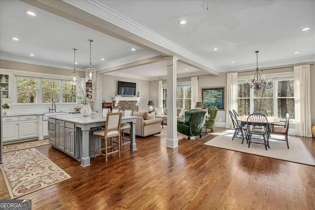 kitchen featuring gray cabinets, white cabinetry, a kitchen bar, a center island, and light stone counters