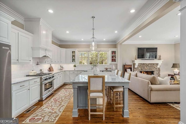 kitchen featuring white cabinetry, light stone counters, a breakfast bar area, and appliances with stainless steel finishes