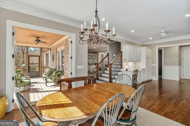 dining area featuring wood finished floors, crown molding, stairs, and ceiling fan with notable chandelier